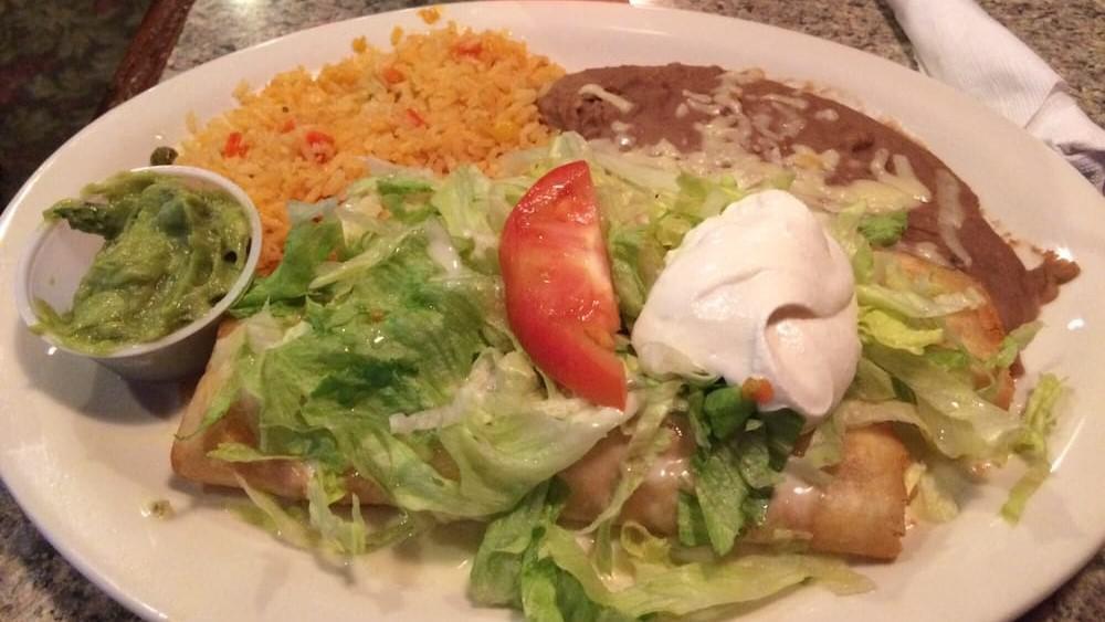 Chimichanga · Two flour tortillas filled with beef or chicken, then deep-fried and topped with melted cheese, red sauce, lettuce, tomatoes, sour cream, and guacamole.