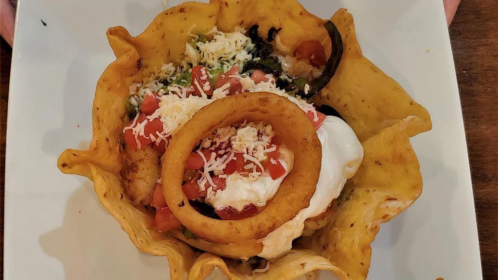 Fajita Taco Salad · Tortilla bowl filled with grilled chicken or steak cooked with peppers and onions topped with lettuce, guacamole, sour cream, tomatoes, and shredded cheese, cucumbers, and an onion ring.