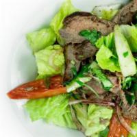 Yum Neua (Beef Salad) · GLUTEN-FREE.  Slightly Spicy. Grilled NY strip steak mixed with cucumbers, onions, tomatoes,...