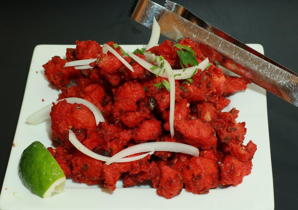 Chicken 65 · A spicy deep-fried appetizer, garnished with onions and cilantro.