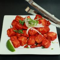 Paneer (Cottage Cheese) 65 · A spicy deep-fried appetizer, garnished with onions and cilantro.