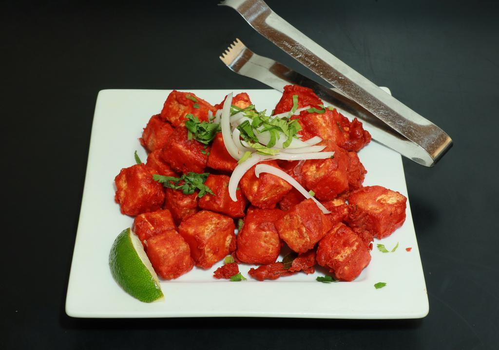 Paneer (Cottage Cheese) 65 · A spicy deep-fried appetizer, garnished with onions and cilantro.