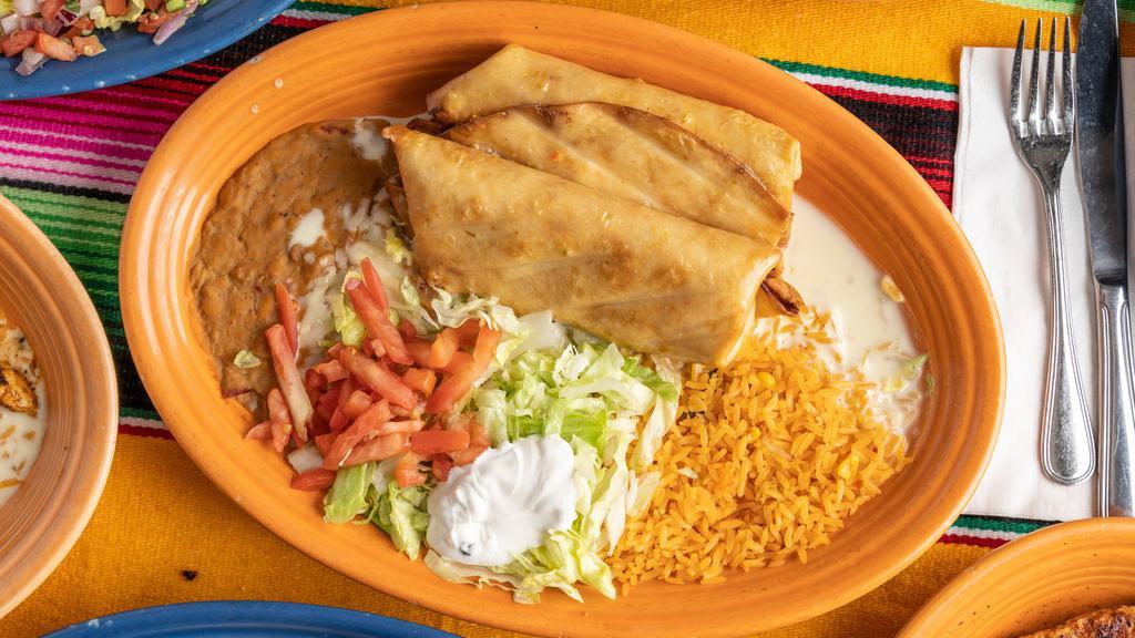 Chimichanga Dinner · Two flour tortillas, fried or soft, filled with shredded beef or chicken, covered with nacho cheese. Served with lettuce, tomato, and sour cream salad, rice and beans.