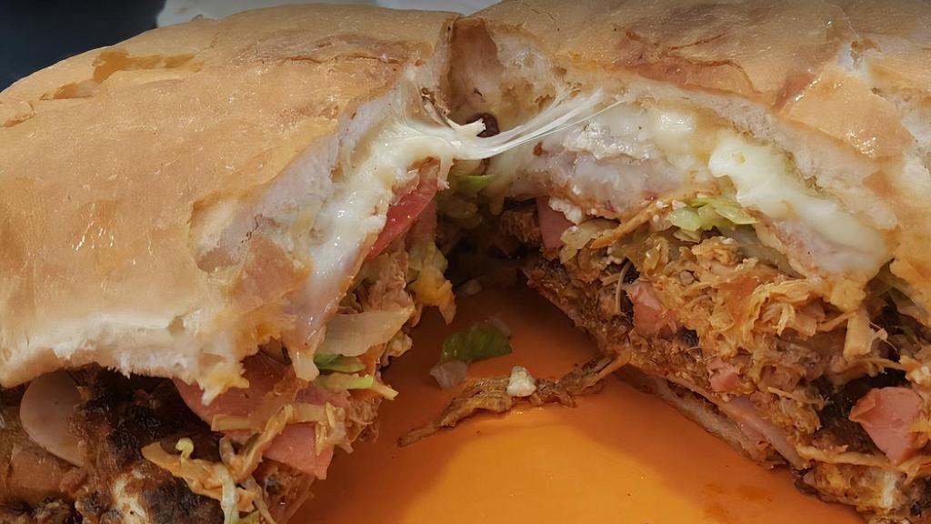 Torta Cubana / Cuban Torta · Res, pollo, cerdo, jamón, salchicha y huevo. Con lechuga, tomate, aguacate, frijoles, cebolla, jalapeños y queso. / Beef, chicken, pork, ham, sausage and egg. Served with lettuce, tomatoes, avocados, beans, onions, jalapeños and cheese.