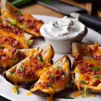 Made-From-Scratch Loaded Potato Skins · Topped with melted cheddar cheese, bacon bits and green onions served with sour cream.