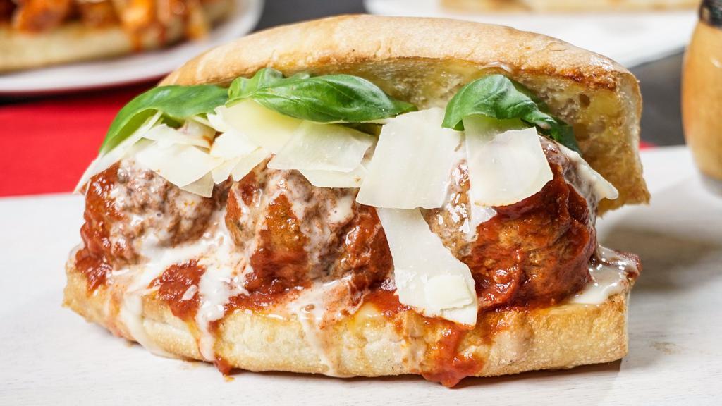 Meatball Parm Sub · Slow-cooked turkey meatballs topped with tomato sauce and cheese melt on a toasted garlic butter roll garnished with shaved parmesan and fresh basil.