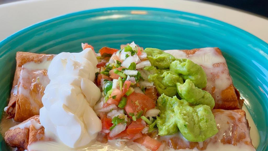 Burritos Fundidos · Two fried burritos, one shredded chicken and one beef tips. Covered with nacho cheese and topped with pico de gallo, sour cream, and guacamole. Served with your choice of rice or beans.