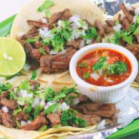 Tacos Carne Asada · Three tacos served with onions, cilantro, lime, salsa, rice, and beans.