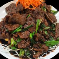Mongolian Beef · Stir-fried beef with onions and scallions served in a sweet brown sauce on top of crispy noo...