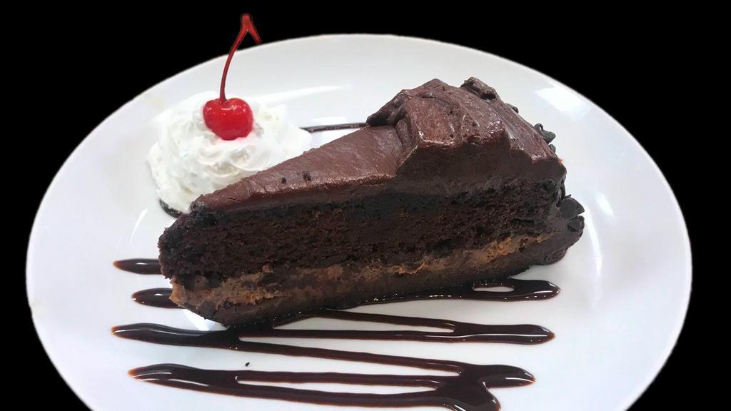 Ultimate Chocolate Cake · Velvety chocolate cake between layers of chocolate decadence and chocolate butter cake on a chocolate cookie crust finished with chocolate ganache and chocolate chips. Decorated with chocolate syrup, whipped cream and a cherry on top.