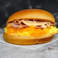Brioche, Ham, Egg, & Cheddar Sandwich · 2 scrambled eggs, melted Cheddar cheese, sliced ham, and Sriracha aioli on a warm brioche bun.