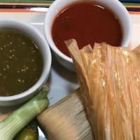 Tamales · Two pork tamales wrapped and steamed in corn husk, topped with our zesty tomatoes, queso sau...