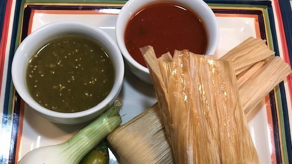 Tamales · Two pork tamales wrapped and steamed in corn husk, topped with our zesty tomatoes, queso sauce, sour cream and guacamole. Served with rice, tortilla chips, salsa fresca and your choice of beans.