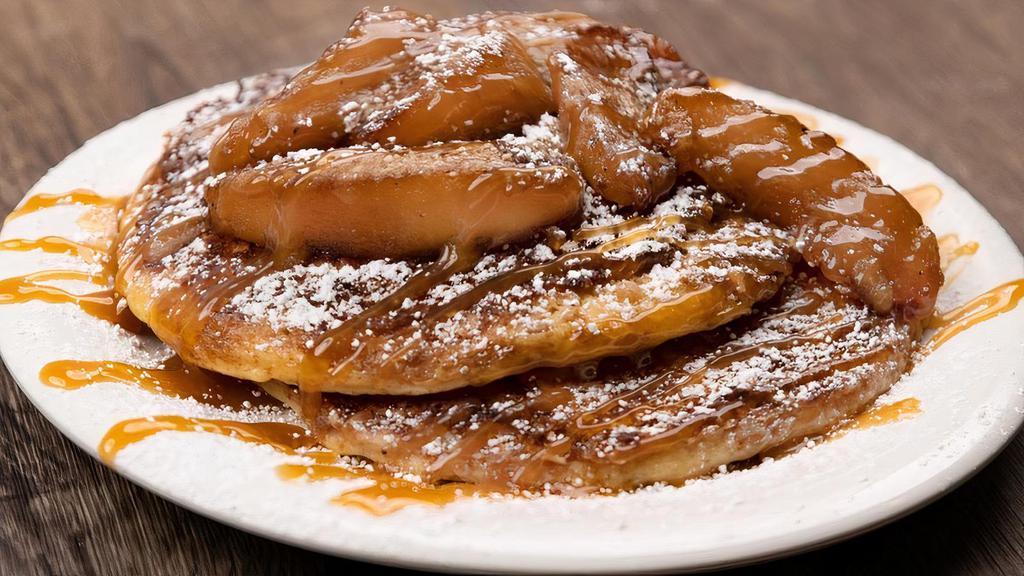 Caramel Apple Pancakes · Two buttermilk pancakes with apple pie crumble griddled-in for a crispy crunch, topped with caramelized fire roasted Fuji apples, caramel sauce and powdered sugar.