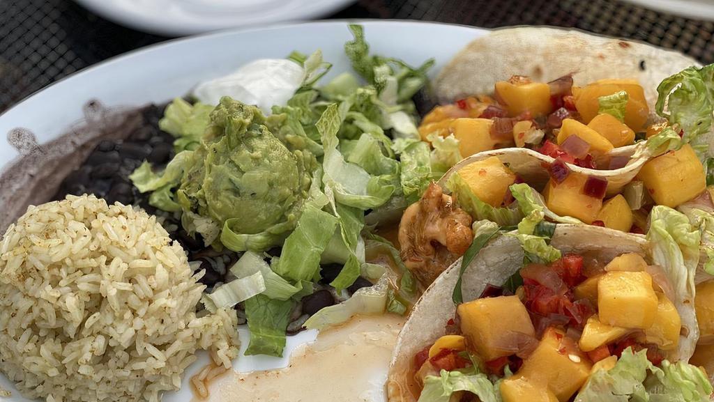 Shrimp Tacos · Three fresh corn tortillas filled with out fire cracker shrimp, crisp lettuce and mango salsa. Served with black beans, cilantro rice, guacamole, and sour cream.