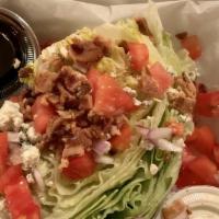 The Wedge Salad -1/2 · Crisp wedge of iceberg lettuce topped with bleu cheese dressing, diced tomato, diced red oni...
