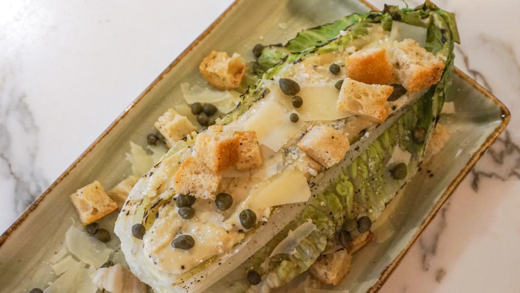 Grilled Caesar Salad · Half head of grilled Romain, Caesar dressing, capers, shaved Parmesan, ciabatta croutons.
