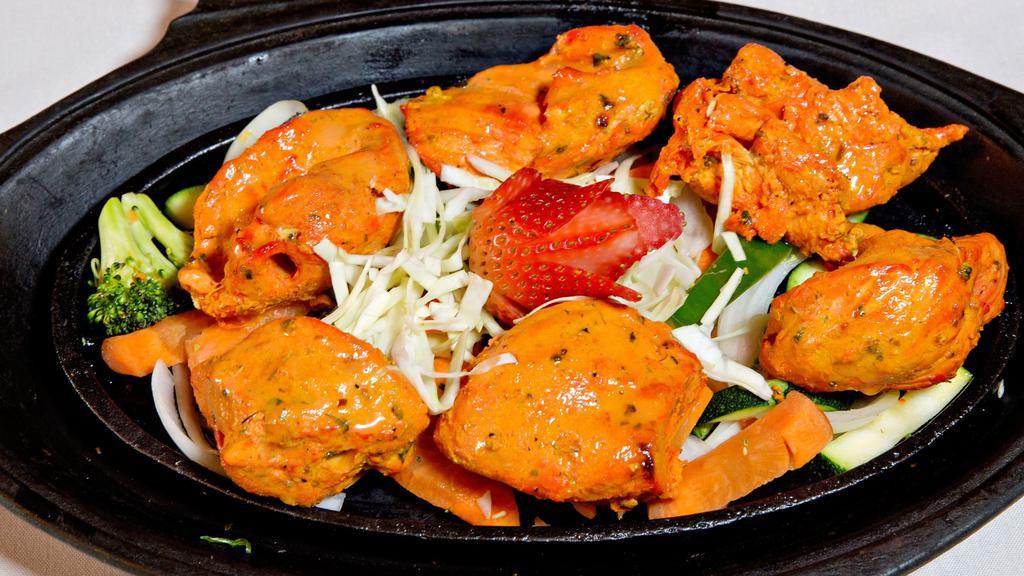 Chicken Tandoori Tikka · Marinated boneless chicken breast cubes. Tandoor is a clay oven, marinated freshly baked to order served on sizzler with fresh cut veggies, low fat herb yogurt or tikka masala sauce on side. Served with choice of rice. Gluten free.