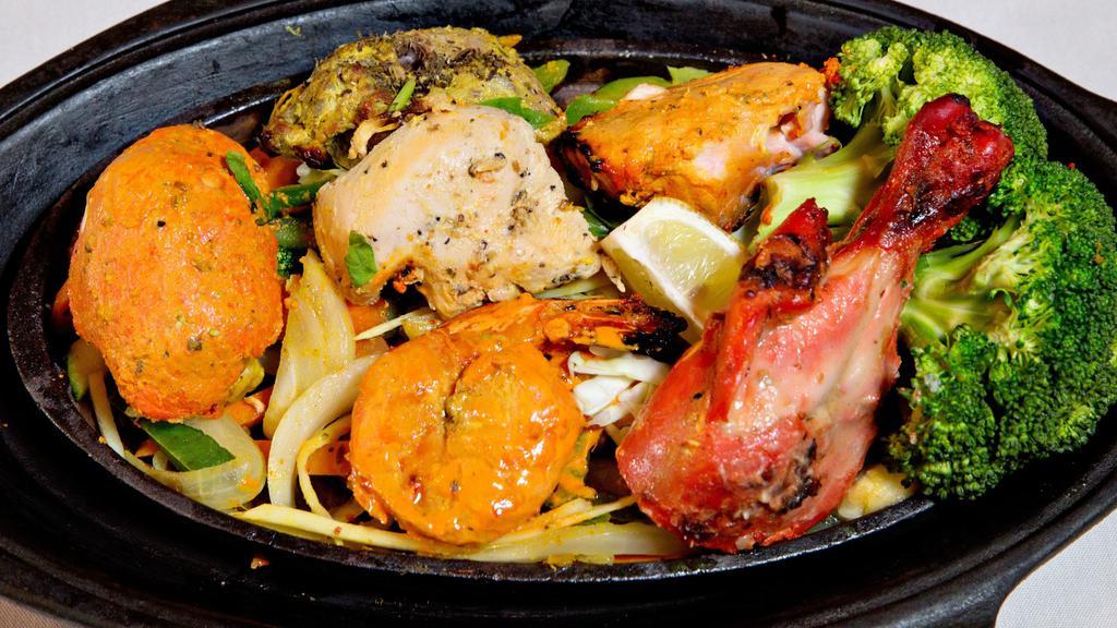 Tandoori Mixed Grill · Assortment of chicken, fish, lamb and shrimp. Tandoor is a clay oven, marinated freshly baked to order served on sizzler with fresh cut veggies, low fat herb yogurt or tikka masala sauce on side. Served with choice of rice. Gluten free.