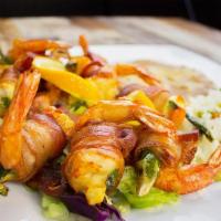 Fiesta Shrimp · Bacon wrapped large prawns braised and served with rice and beans .