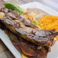 Costillas Asadas De Res * · Roasted beef ribs served with rice and beans , guacamole and pico de gallo .