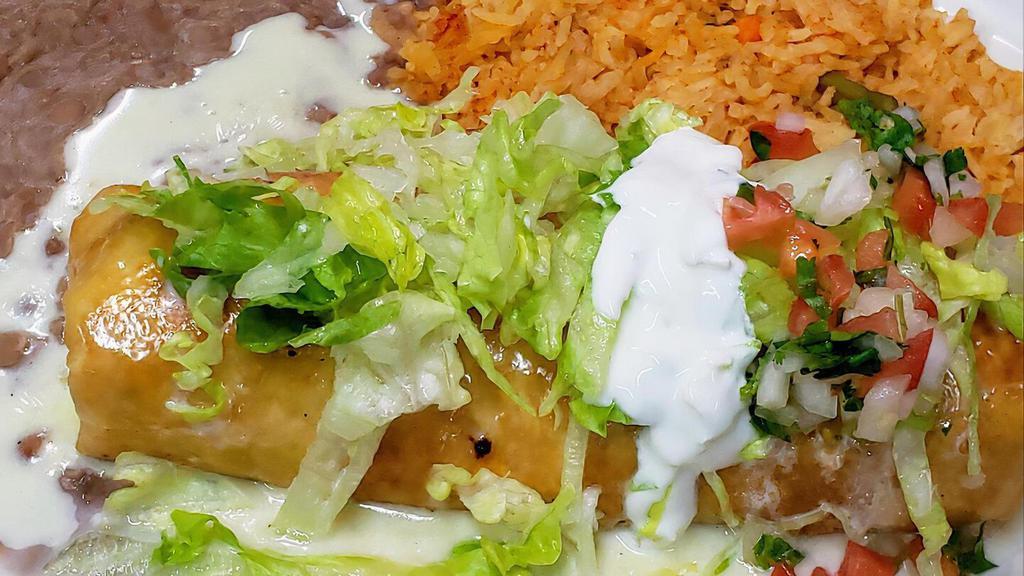 Chicken Chimichanga · Fried burrito topped with queso, lettuce, sour cream, pico de gallo and guacamole served with a side of rice and beans.