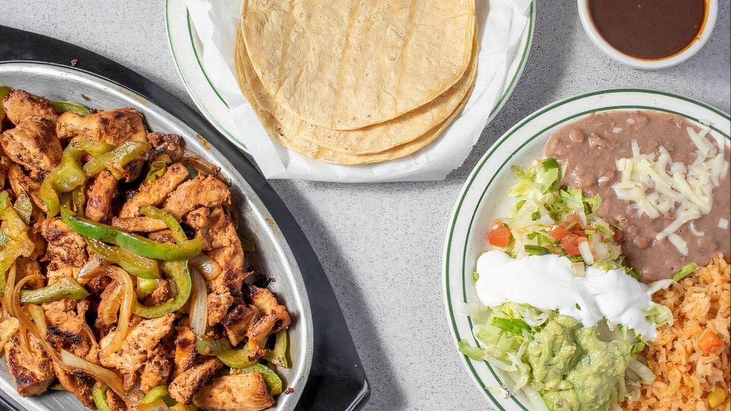 Fajitas · Steak or chicken, grilled onions, bell peppers, rice, refried beans, tortillas, lettuce, sour cream, lime, pico de gallo, guacamole, and salsa.