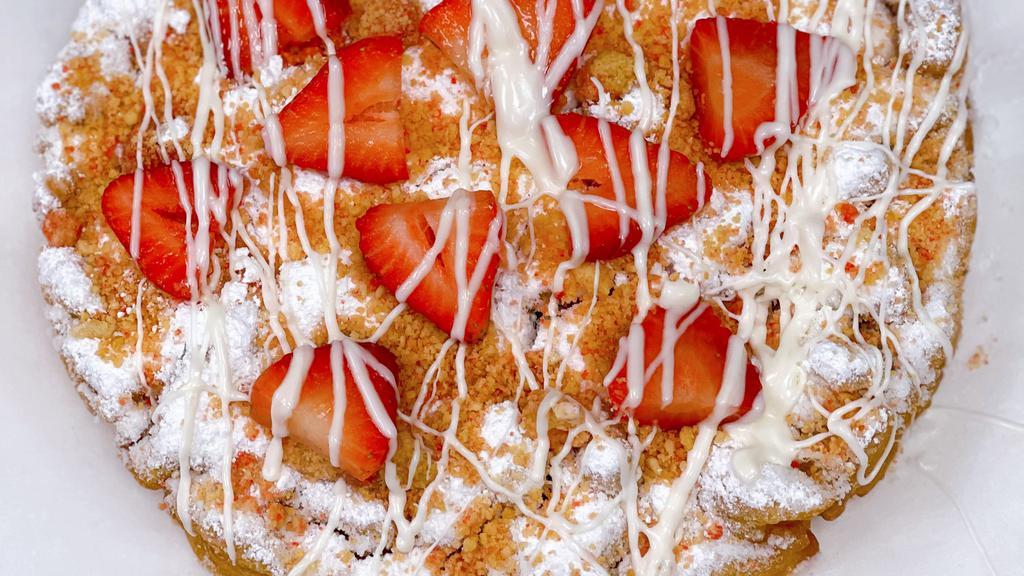 Strawberry Crumble Funnel Cake · Freshly made funnel cake topped with powdered sugar, fresh cut strawberries and our signature strawberry crumble mixture then drizzle with white chocolate!