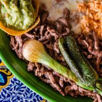 Carne Asada · Marinated top sirloin steak topped with grilled onions. Served with rice, beans, guacamole s...