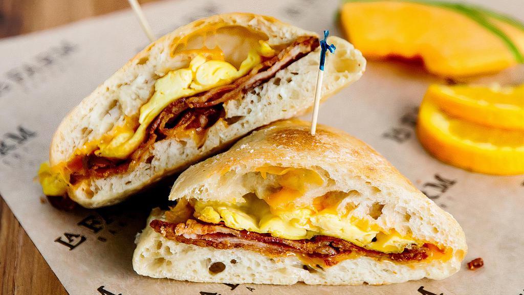 Deluxe Breakfast Sandwich · Farm fresh scrambled eggs, aged cheddar, choice of bacon, ham or sausage, served with a side of fruit