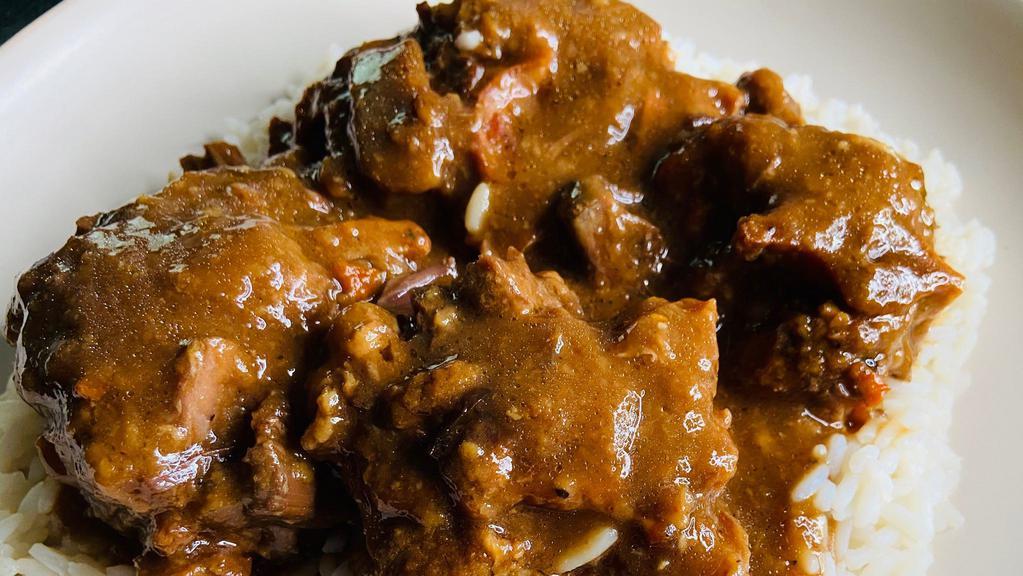 Oxtails · Oxtails in gravy on rice with two sides.