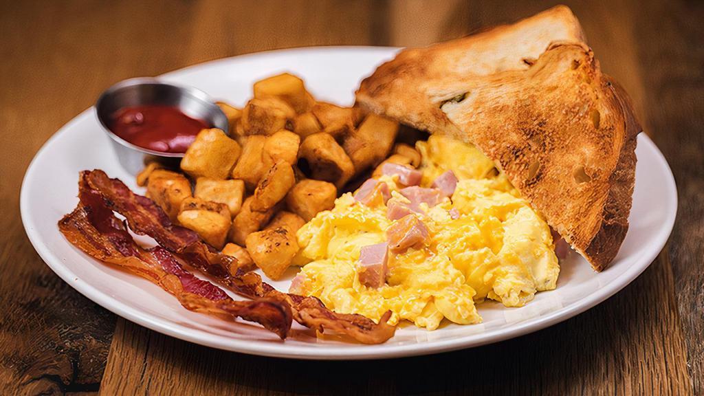 Ham Scrambler · Three eggs scrambled with ham and cheddar cheese, your choice of applewood smoked bacon or maple sausage links, served with hashbrowns and your choice of Toast.