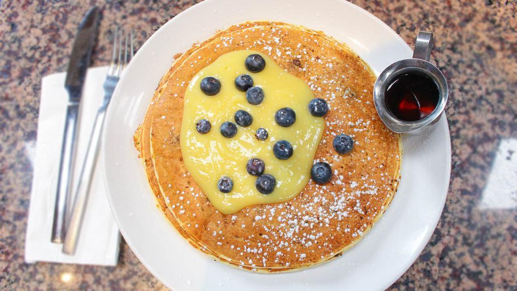 Blueberry & Lemon Curd Flapjacks · Three jumbo flapjacks with fresh blueberries topped with a light lemon curd, powdered sugar, and served with warm maple syrup.