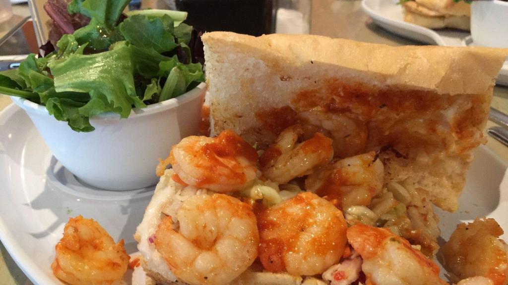 Bbq Shrimp & Grits · Spicy dark shrimp roux over creamy grits with sliced baguettes.