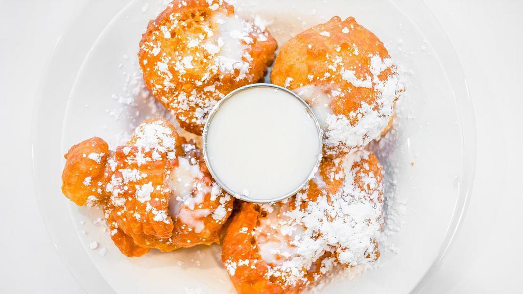 Pancake Beignets · Homemade pancake batter, deep fried & filled with sweetened cream cheese. served with your choice of dipping glaze caramel, vanilla, or chocolate.