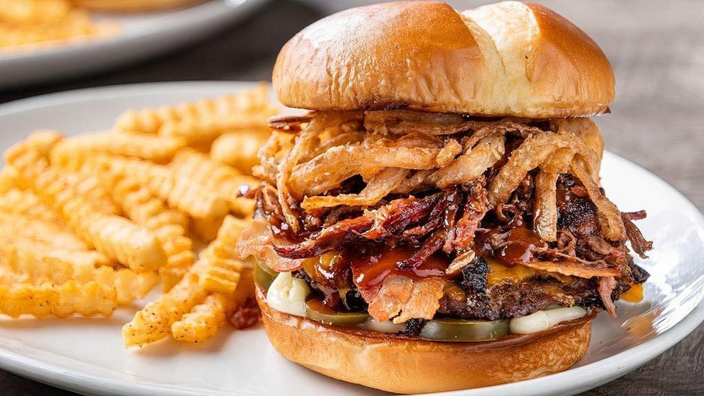 Smokehouse Burger · A grande size burger topped with bacon and shredded beef brisket, layered with jalapeño-BBQ sauce, cheddar cheese, pickled jalapeños, mayo and fried onion strings.  Served with fries.. Add sliced jalapeño sausage to amp up your burger!
