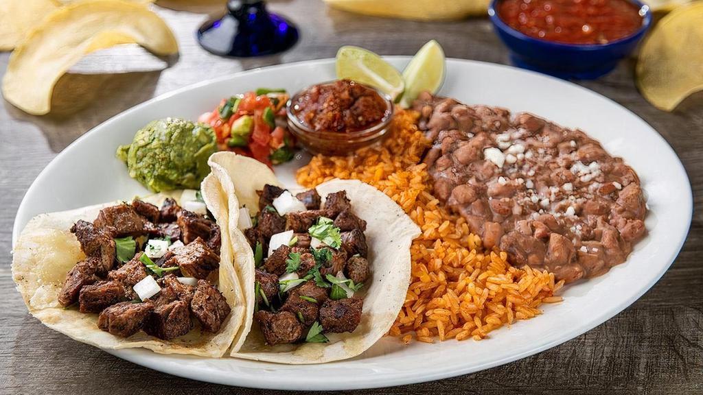 Tacos Al Carbon · White corn tortillas with fajita chicken or steak, Jack cheese, diced onion and chopped cilantro. Served with pico de gallo, fresh guacamole, roasted red chile tomatillo salsa, Mexican rice and choice of beans.