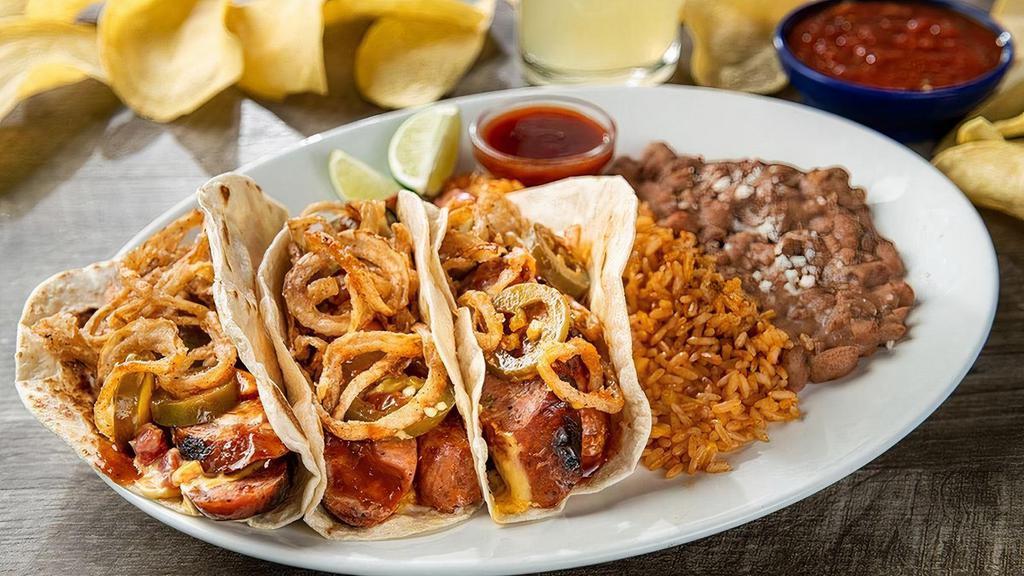 Mesquite Smoked Jalapeño Sausage Tacos · Jalapeño sausage, Signature Queso, jalapeño BBQ sauce, fried onion strings and pickled jalapeños wrapped in hand-pressed flour tortillas.  Served with Mexican rice and choice of beans.