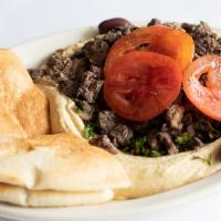 Shawerma Hummus · Served over a bed of hummus with parsley, onions, grilled tomatoes, and pita bread.