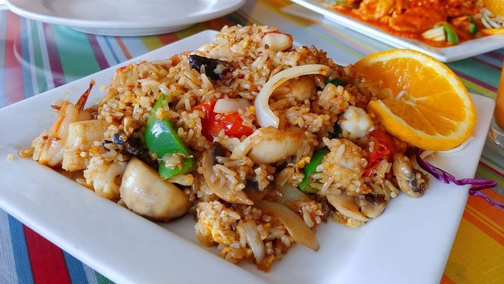 Phooket Fried Rice · A mouth-watering combination of shrimp, scallop, squid, imitation crab meat, mussels, fresh Thai basil leaves, onions, bell peppers, tomatoes, mushrooms, carrots, baby corn, and bamboo shoots.  Stir-fried with jasmine rice in our signature sweet and tangy chili brown sauce. Due to supply chain issues we may be out of certain ingredients.