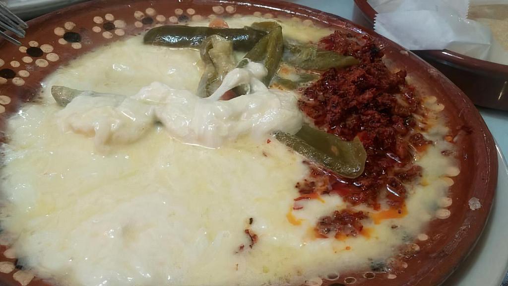 Queso Fundido · Melted cheese mixed with chorizo and grilled veggies.