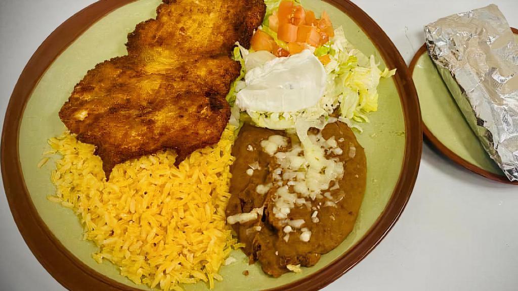 Milanesa · Thinly sliced breaded chicken or steak fried to a golden brown, served with lettuce, tomato, sour cream, rice and beans.