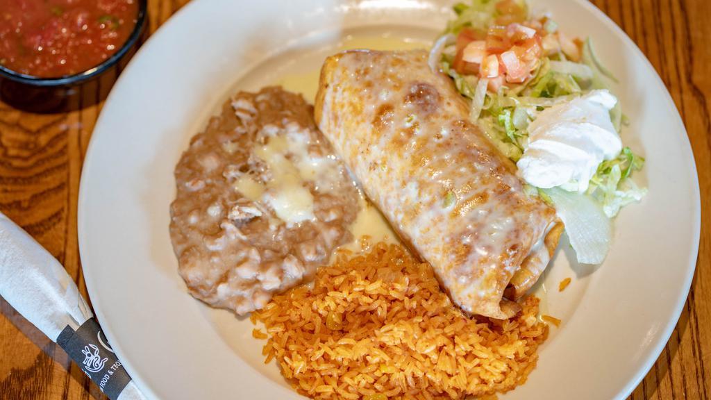 Chimi Rica · Grande. Flour tortilla, soft or fried, wrapped in ground beef or pulled chicken, topped with queso, sour cream, tomatoes and lettuce. Served with rice and beans. Substitute grilled steak, chicken or shrimp for an additional charge.