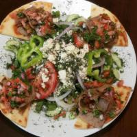Gyro Plate. · Gyro meat thinly sliced and served on pita bread, topped with tomatoes and onions, with a Gr...