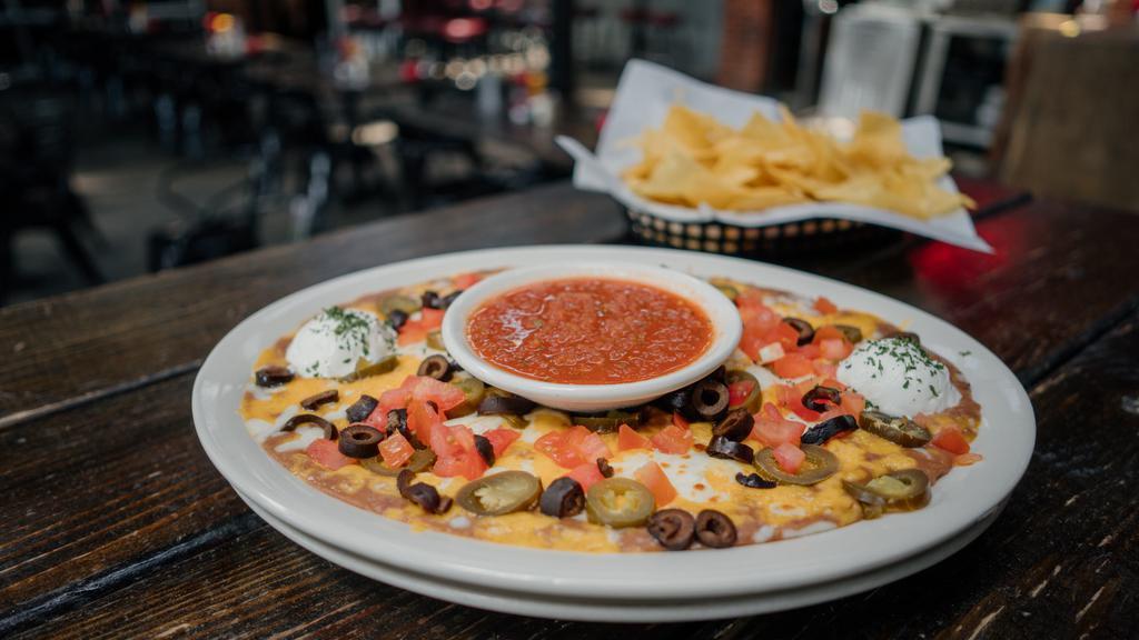 Nachos · fresh tortilla chips, refried beans, black olives, diced tomatoes, cheddar cheese, mozzarella cheese, sour cream, jalapeños & served w/ salsa