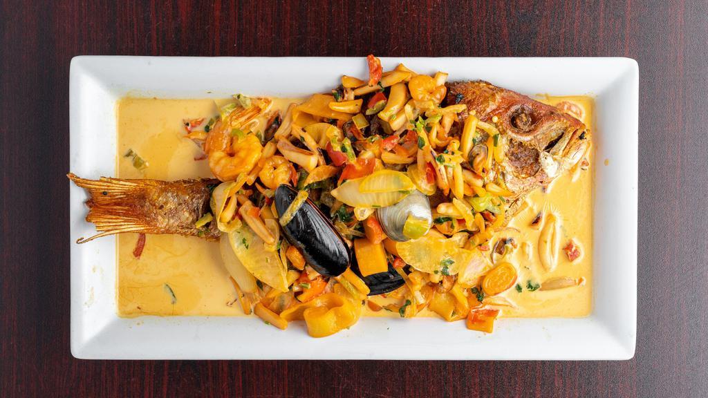 Pargo Marinado · Red snapper topped with creamy seafood sauce, served with rice and green plantains.
