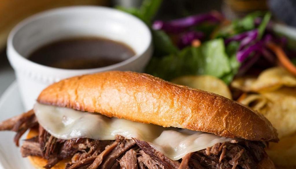 French Dip · Shaved Rib Eye, Sautéed Onions, Provolone cheese, served with Fries, Au Jus, Coleslaw and Pickle Spear.
