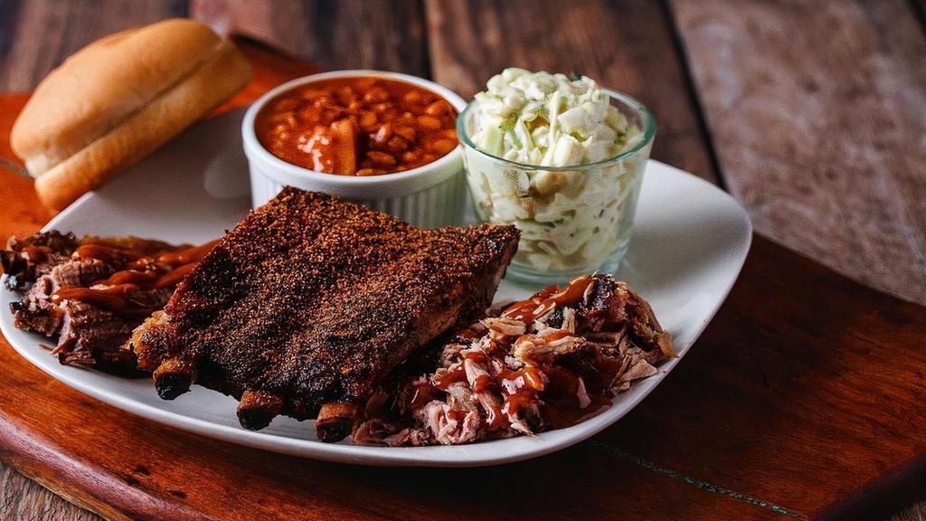 Sampler Plate · Chopped pork shoulder, sliced beef brisket, and 1/4 slab of ribs served with two sides, a toasted bun, and sweet and mild BBQ sauces.