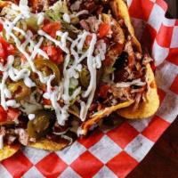 Loaded Bar-B-Q Nachos · Smoked, chopped pork shoulder on a bed of tortilla chips topped with white queso, Tops famou...
