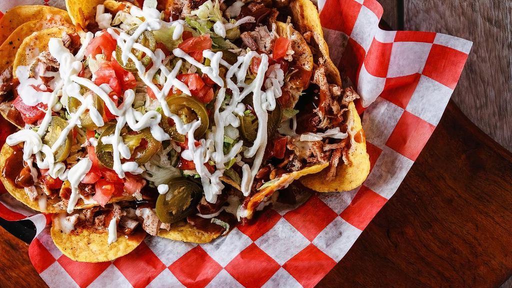 Loaded Bar-B-Q Nachos · Smoked, chopped pork shoulder on a bed of tortilla chips topped with white queso, Tops famous BBQ beans, lettuce, tomatos, onions, jalapenos, original mild BBQ sauce, and our signature rub.